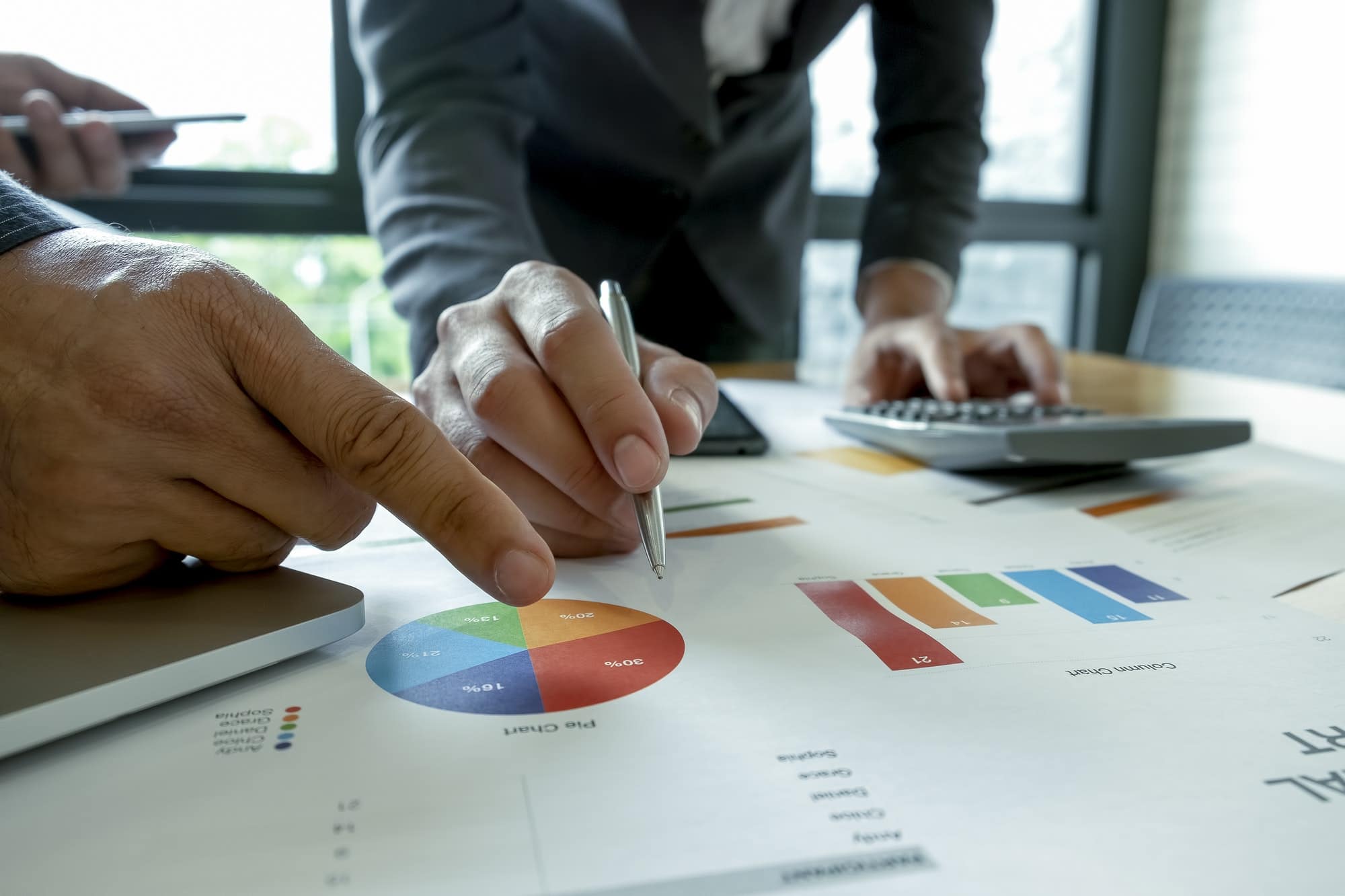 Business team is analyzing graphs on the desk.